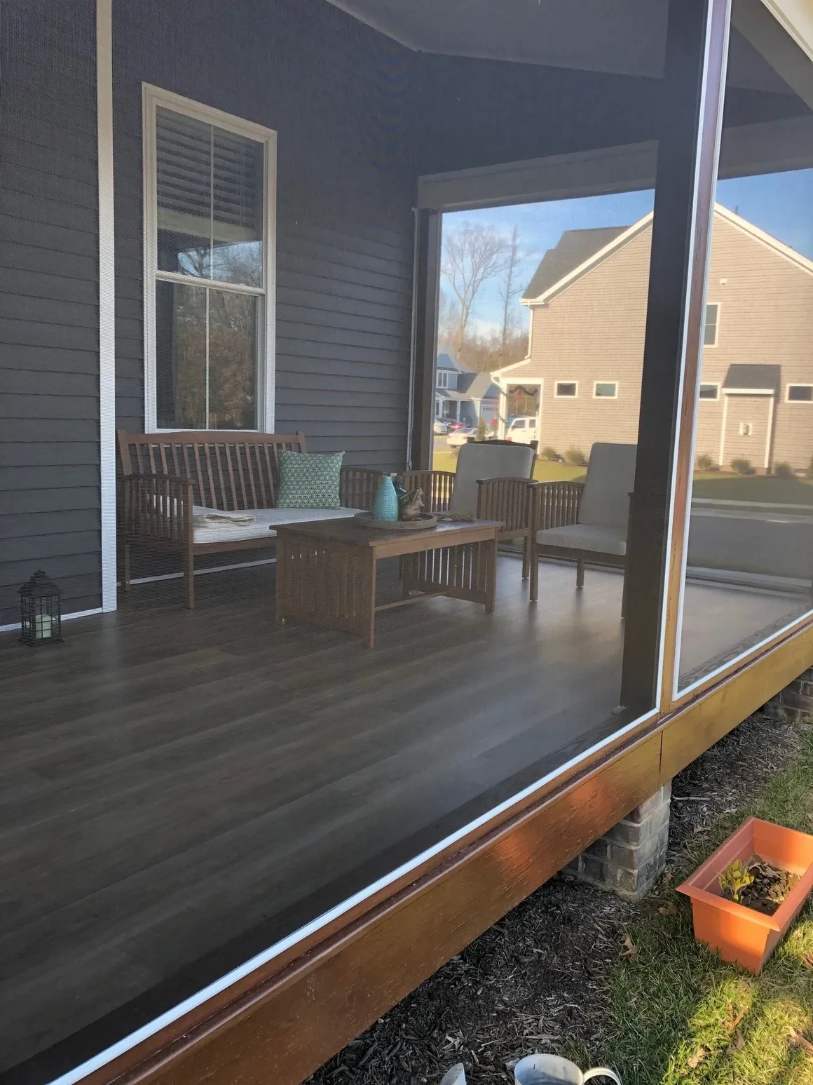 Screened porch with wooden furniture and backyard views