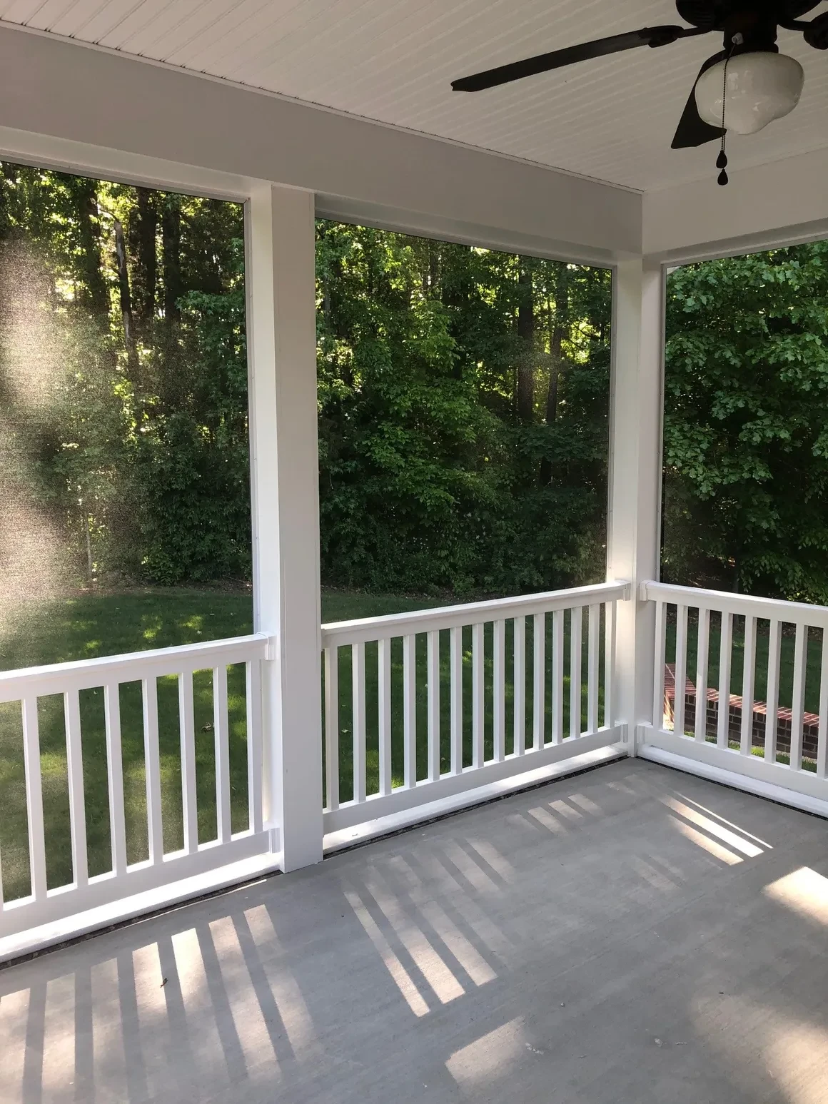 Screened porch with white railings and forest view