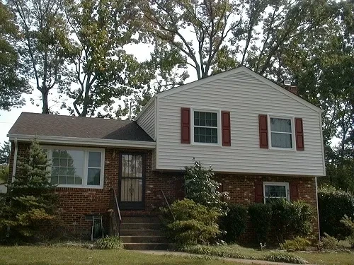 Brick house with red shutters and trees