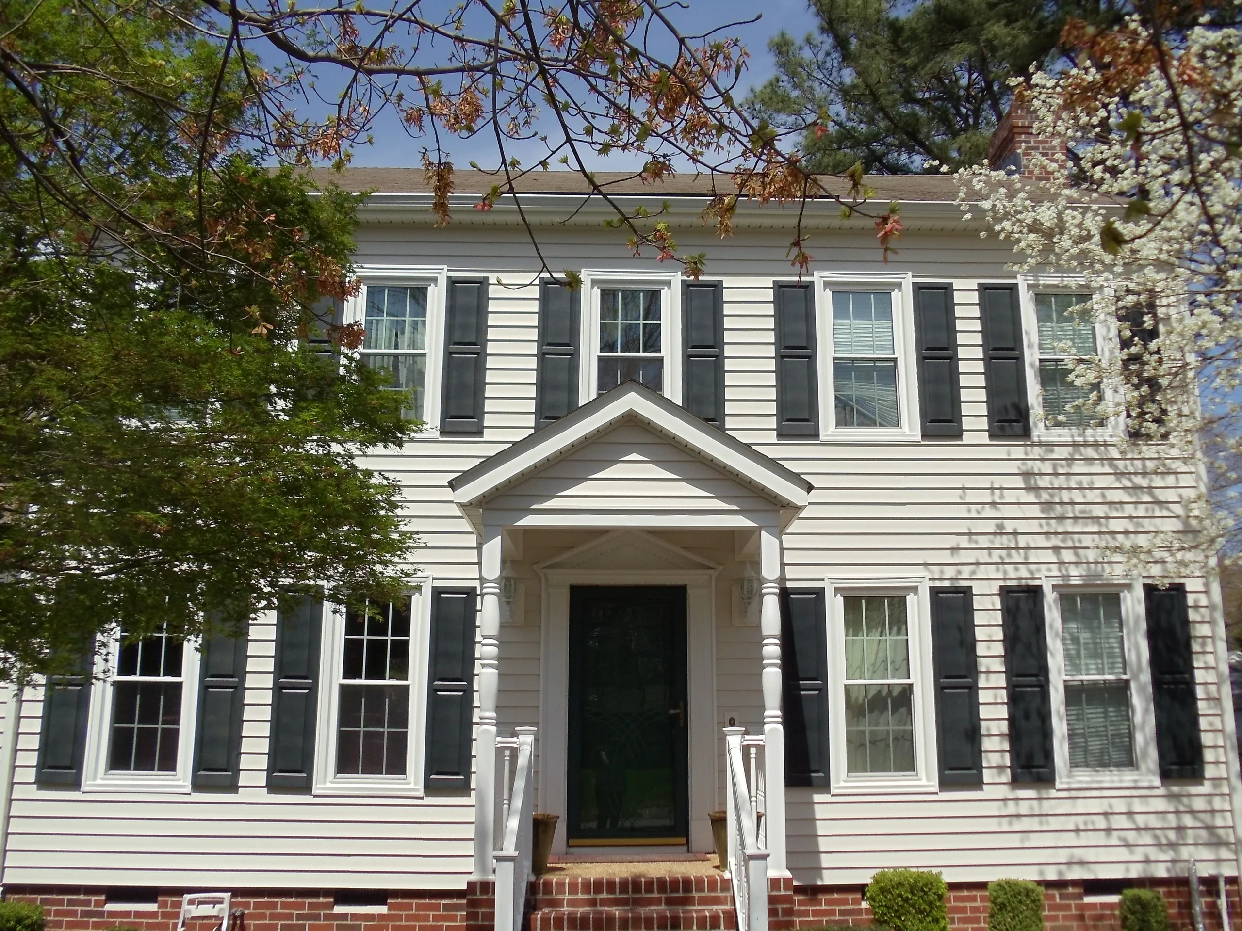 White colonial house black shutters brick foundation